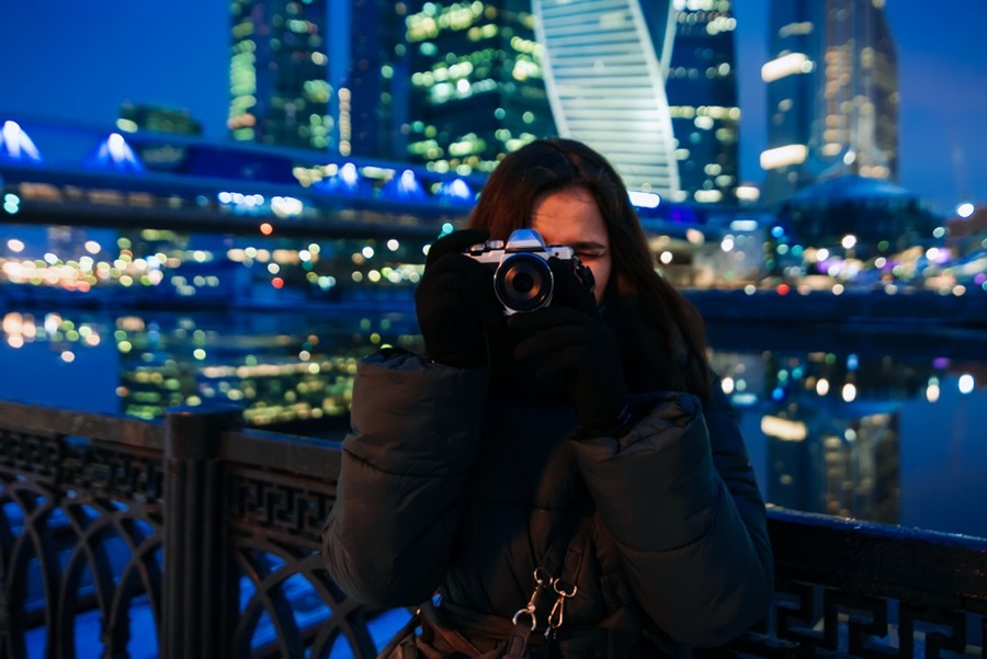 donna con una macchina fotografica intenta a scattare una foto